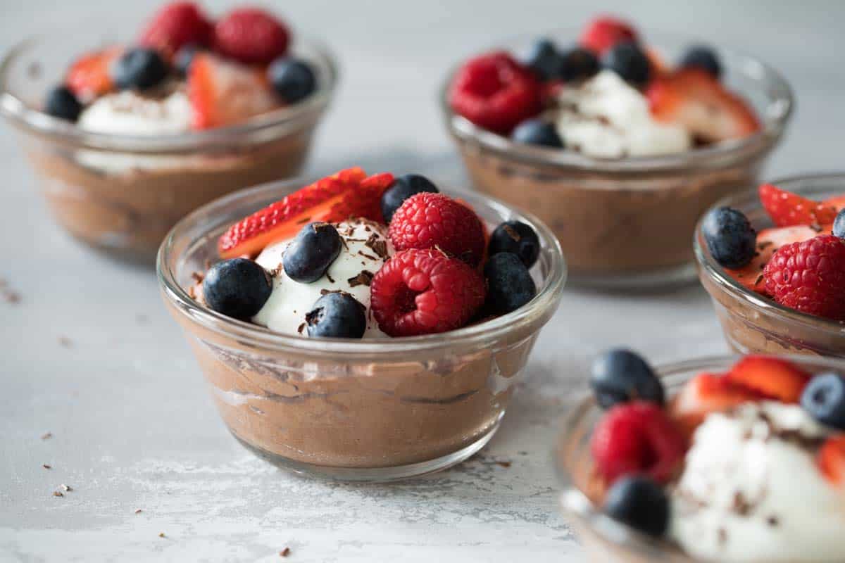 bowls of chocolate mousse topped with berries and whipped cream