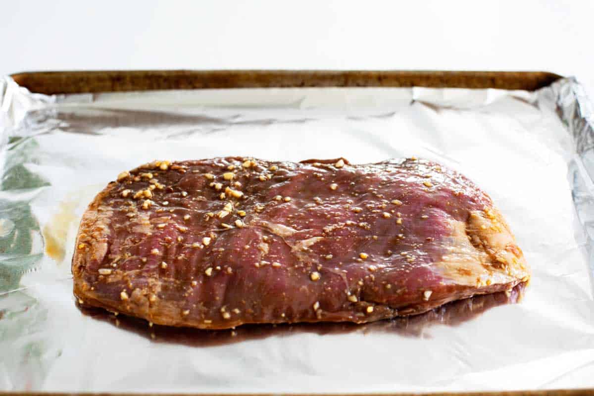 marinated flank steak on a baking sheet