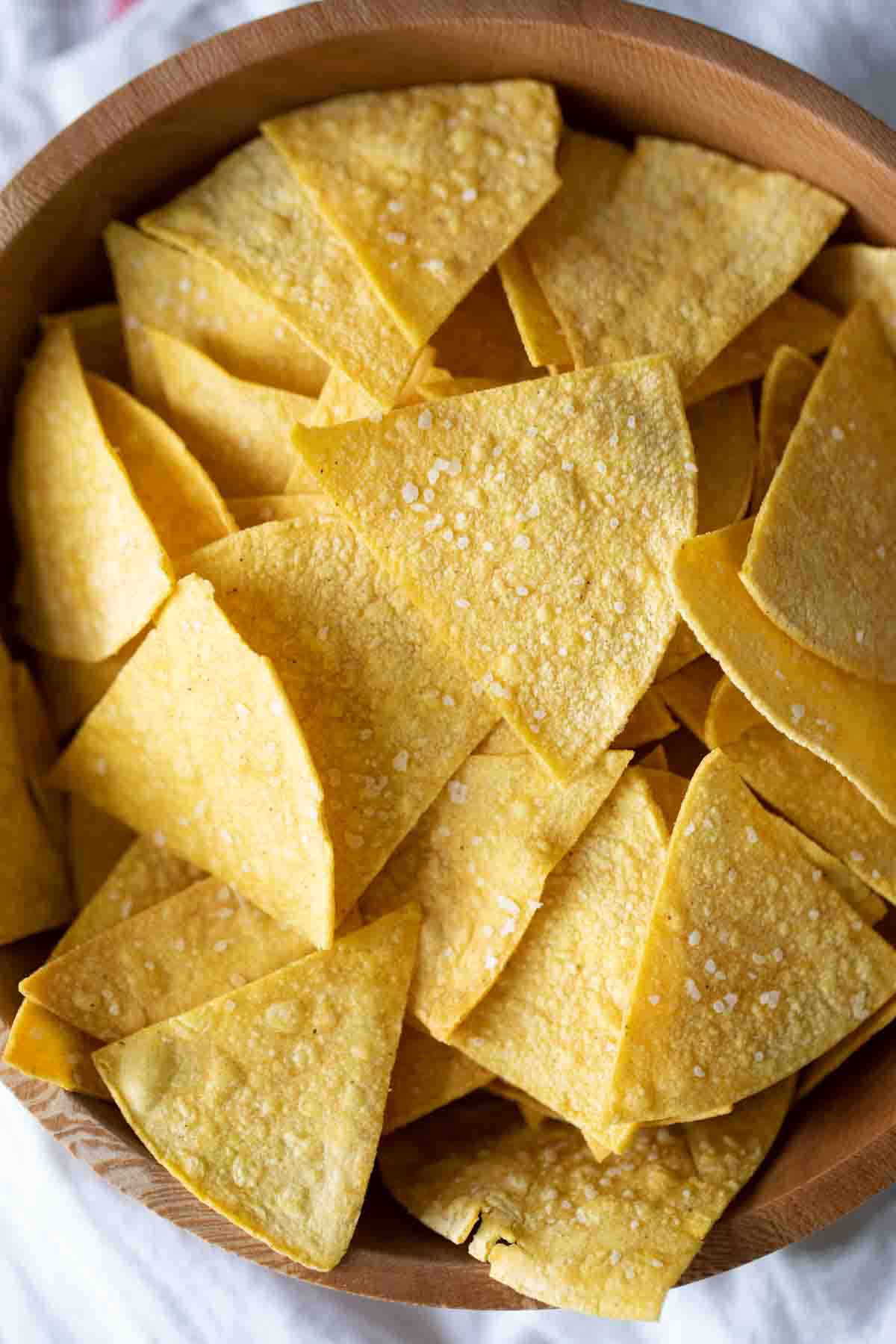 Crispy and salty, these Homemade Tortilla Chips are so easy to make and so much better for you than store bought. They are the perfect afternoon snack. overhead view of a bowl of tortilla chips
