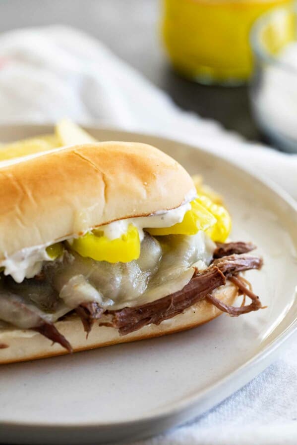 Slow Cooker Italian Beef Sandwich with cheese and peppers on a plate