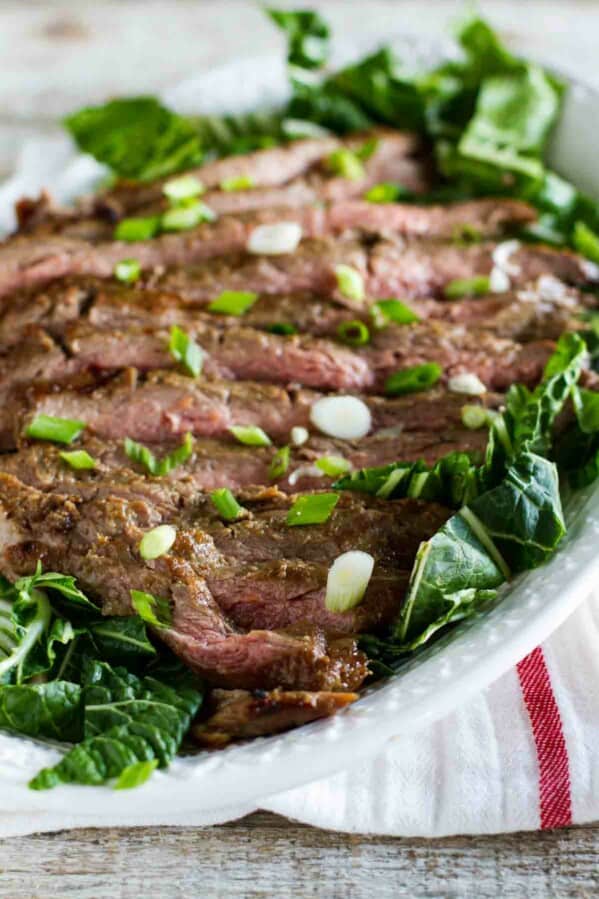 Korean Barbecue Flank Steak on a plate with greens