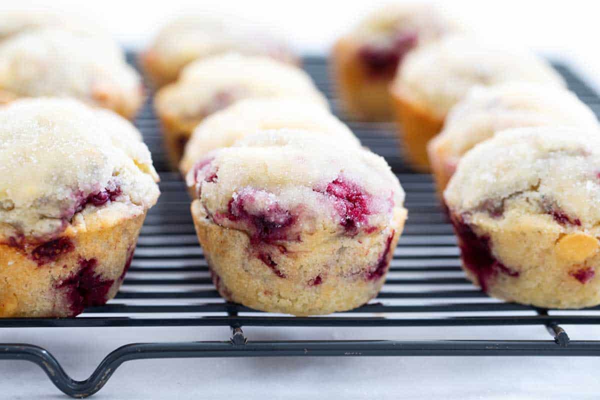 raspberry muffins with white chocolate chips on a cooling rack
