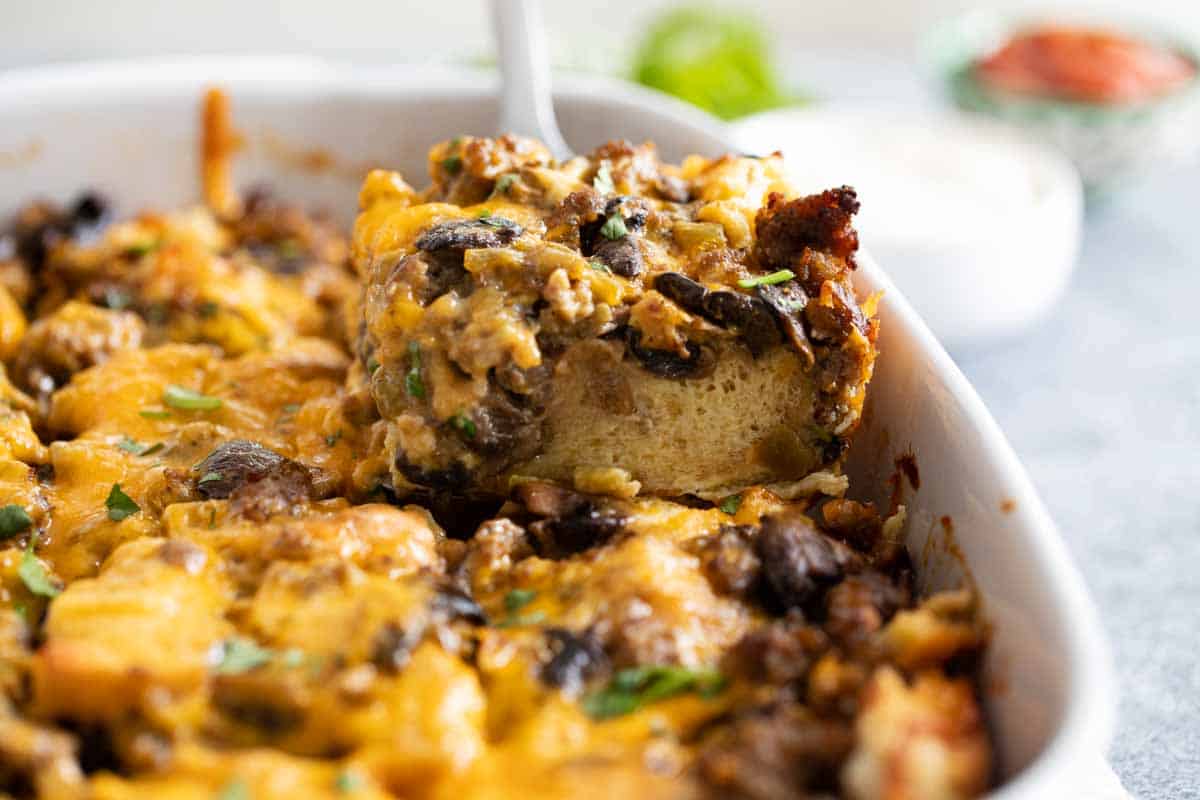 Filled with sausage, mushrooms and green chiles, this Sausage Breakfast Casserole is hearty and filling. Plus, all of the work is done the night before, which makes breakfast a snap! getting slice of breakfast casserole from dish