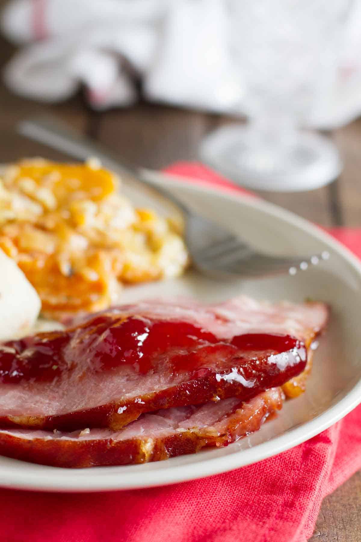 slices of Brown Sugar and Cherry Glazed Ham on a plate with side dishes