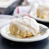 Cinnamon roll with icing on a white plate