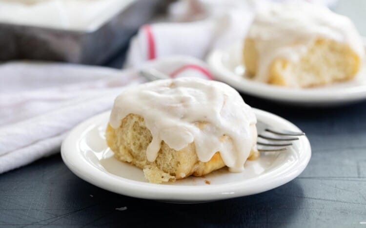 Cinnamon roll with icing on a white plate