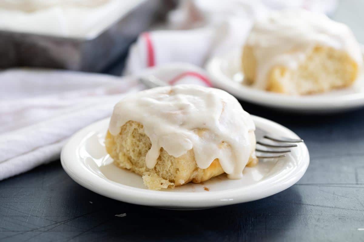 Cinnamon roll with icing on a white plate