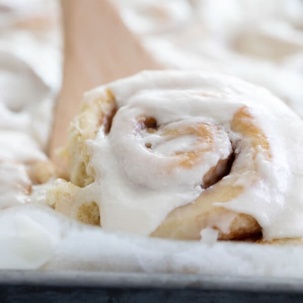 removing a cinnamon roll from the pan