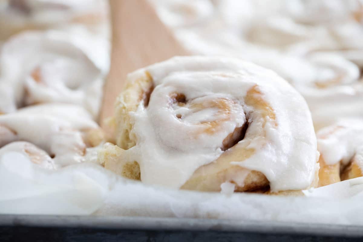 removing a cinnamon roll from the pan