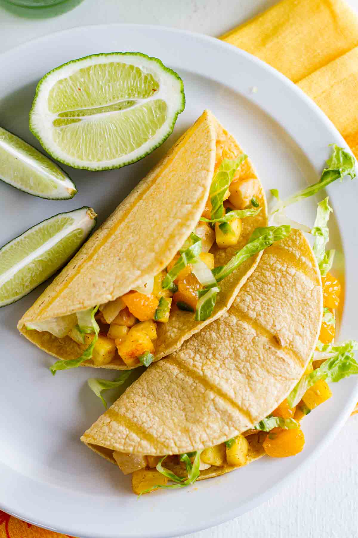 overhead view of citrus fish tacos with fruit salsa with limes on the plate