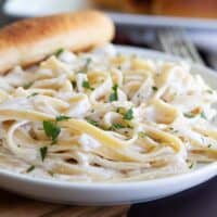 plate with fettuccine with alfredo sauce and a breadstick