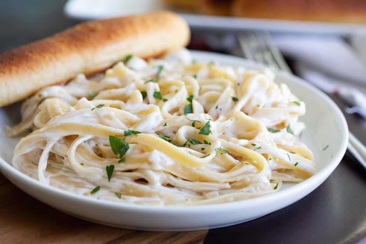 plate with fettuccine with alfredo sauce and a breadstick