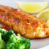 Parmesan Crusted Tilapia on a plate with lemons and broccoli