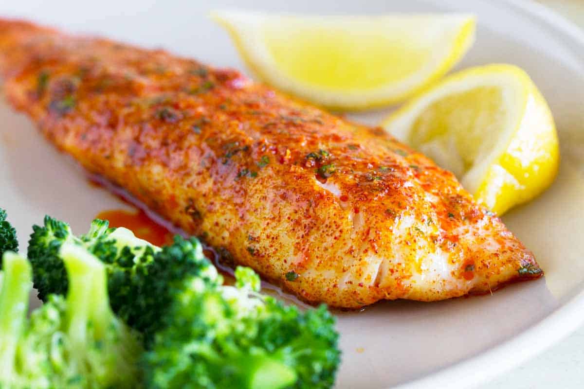 Parmesan Crusted Tilapia on a plate with lemons and broccoli