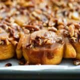 caramel sticky buns on a tray topped with pecans