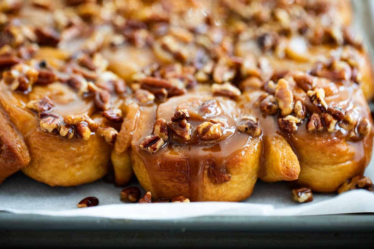 caramel sticky buns on a tray topped with pecans