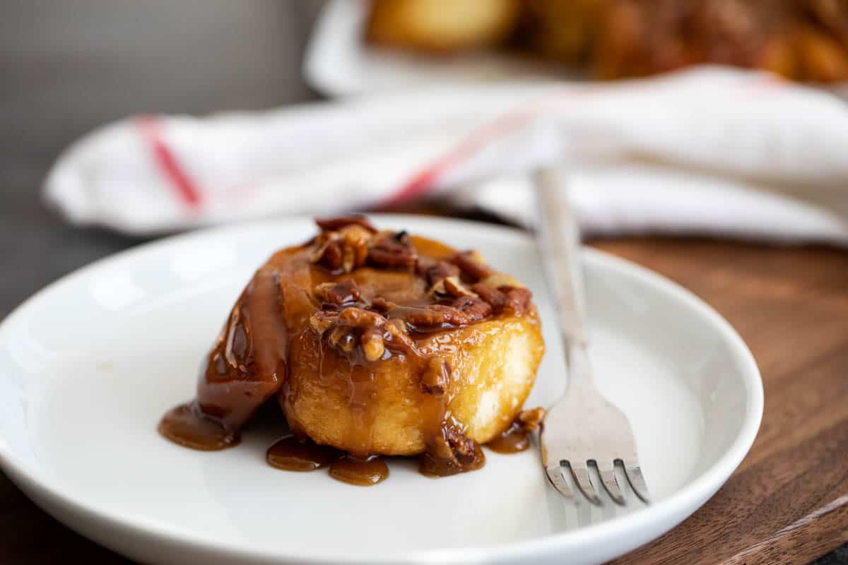 single sticky bun on a plate with a fork