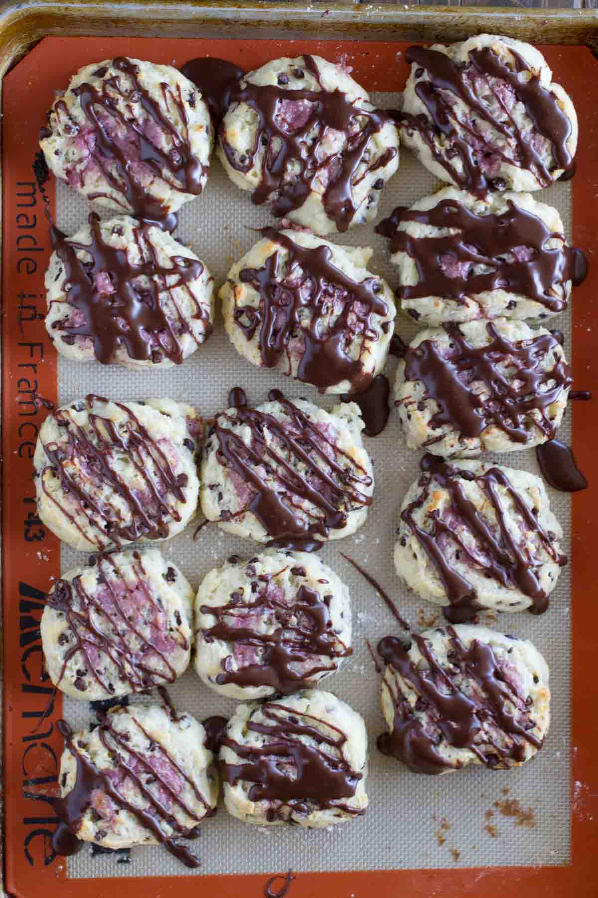 overhead view of chocolate chip biscuits with raspberry cream on a baking sheet