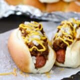 2 Coney Island Hot Dogs topped with mustard, cheese and onions