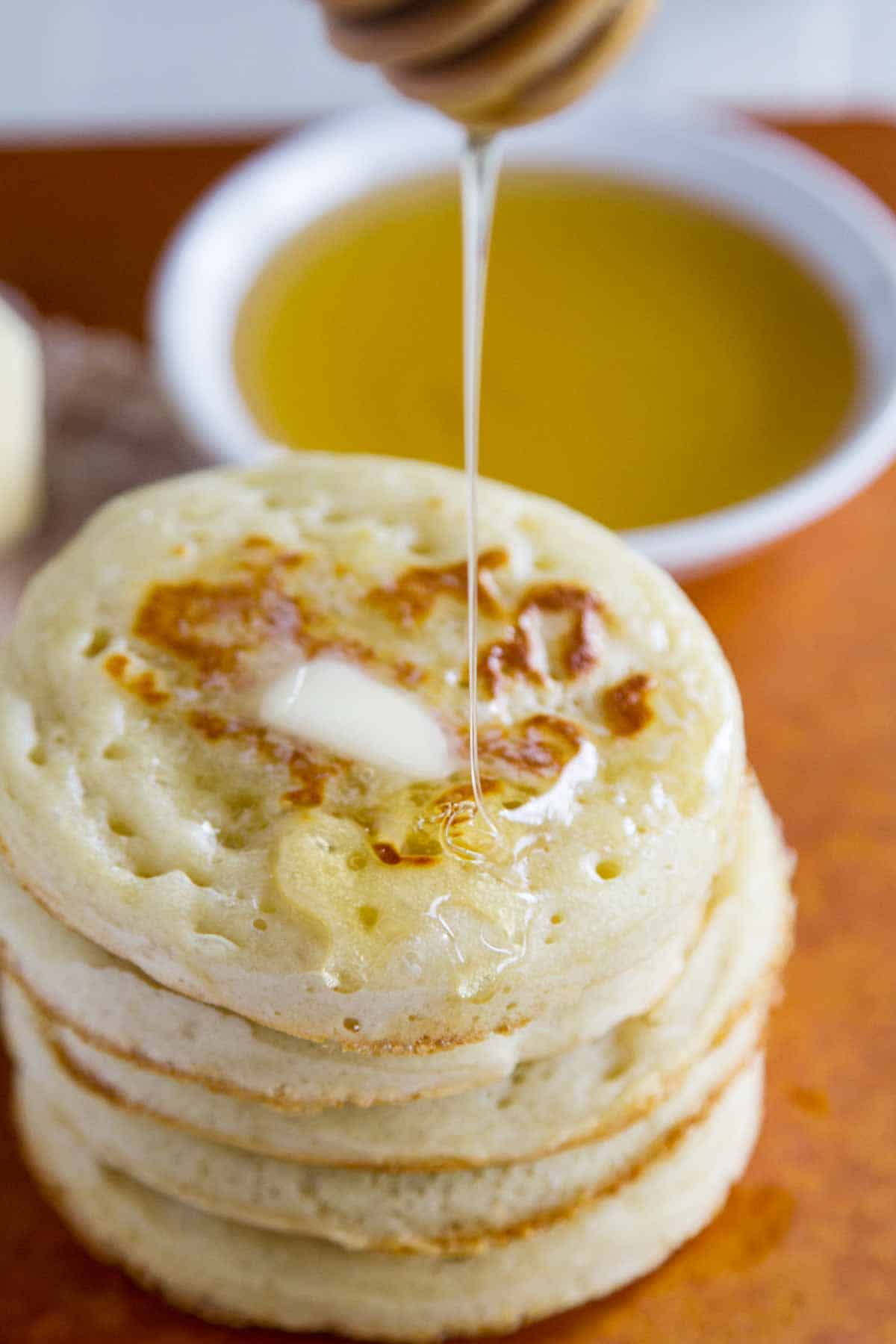 stack of homemade crumpets with butter with honey drizzle