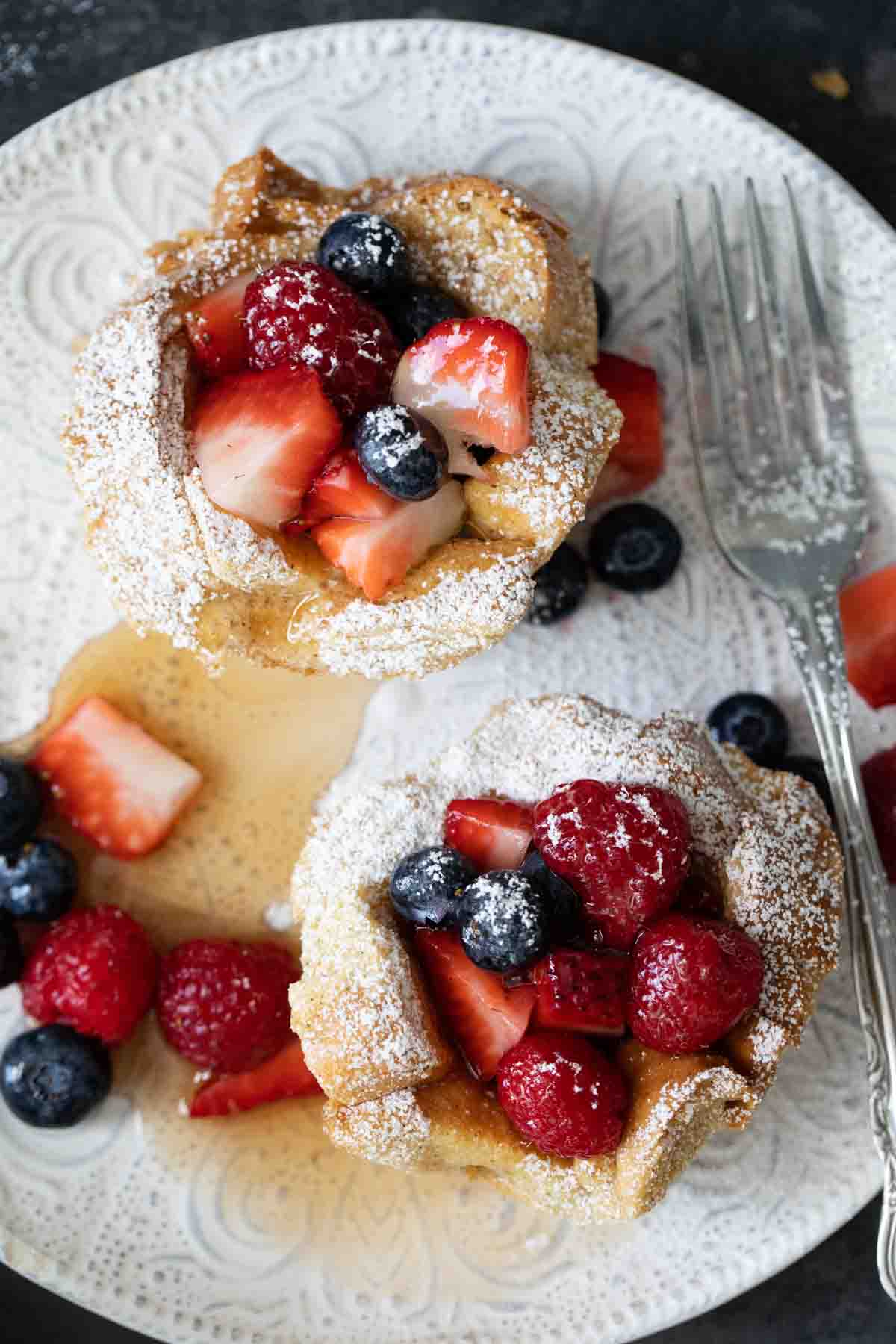 overhead view of individual french toast with berries and syrup