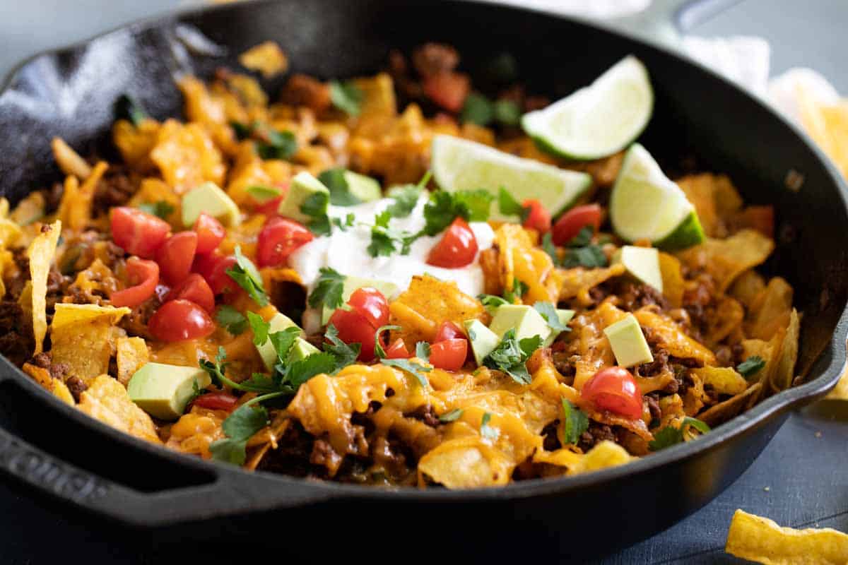 Looking to change up taco night? This Taco Skillet is easily made in one pan and is on the table in 30 minutes. It’s a dinner the whole family will love. taco skillet in a cast iron skillet with toppings