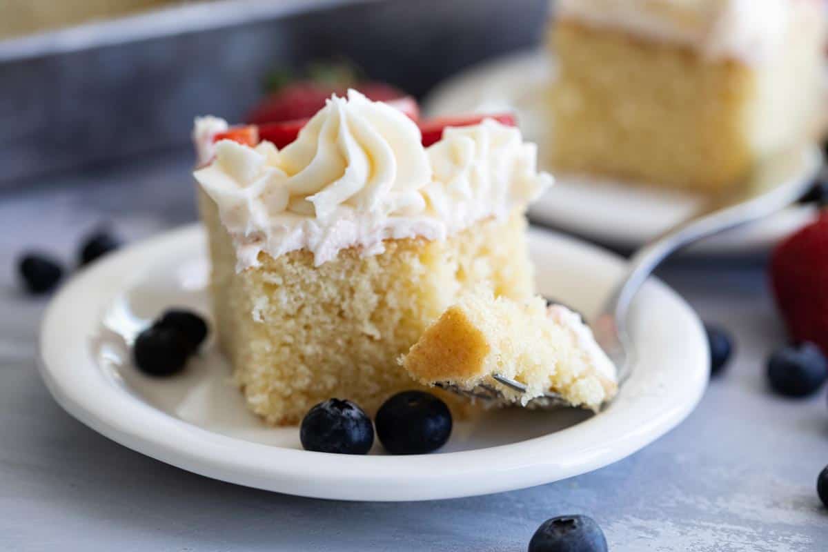 fork in white cake with buttercream and fruit