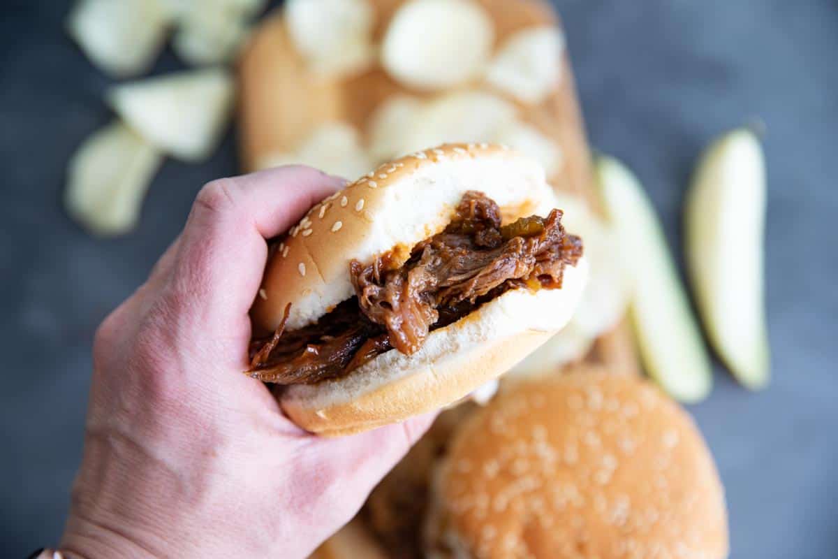 bbq beef sandwich being held with bite taken from it