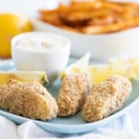 homemade fish sticks on a blue plate with lemons