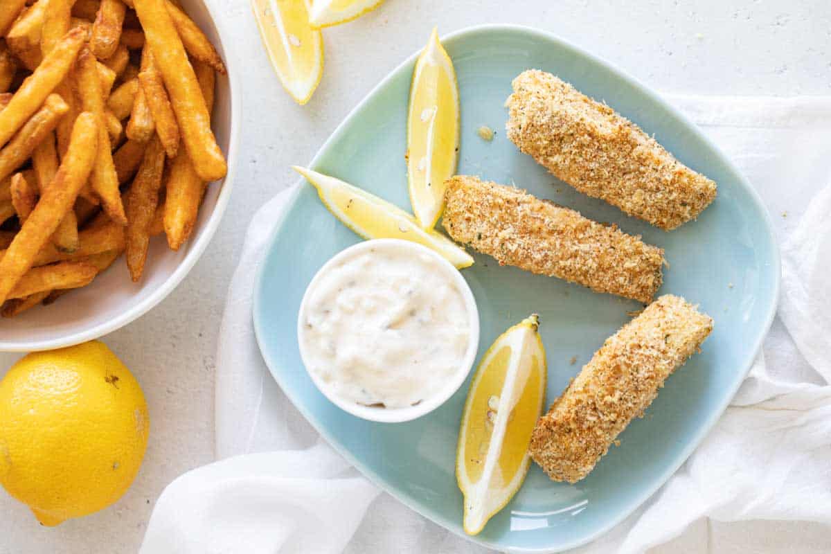 overhead view of fish sticks on a plate with tartar sauce and fries