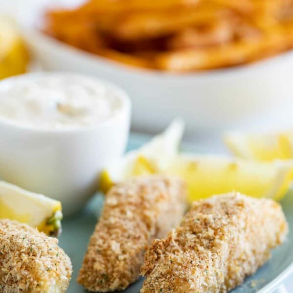 Homemade fish sticks on a plate with fries in the background