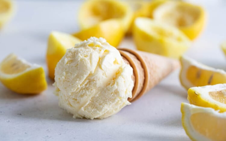 ice cream cone topped with ice cream with lemons in the background