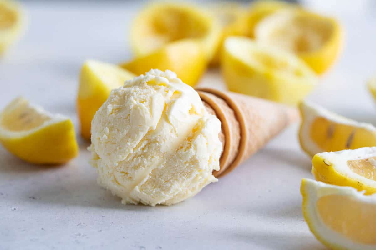 ice cream cone topped with ice cream with lemons in the background