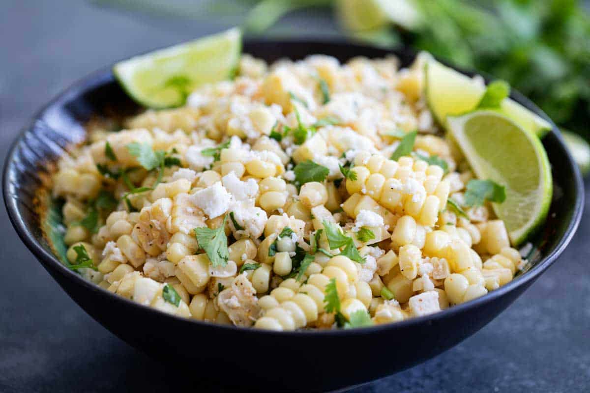 bowl of Mexican Corn Salad with limes and cilantro