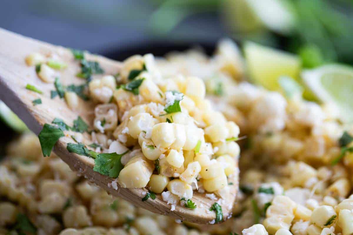 scooping Mexican corn salad with wooden spoon