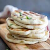 a stack of naan bread on a cutting board sprinkled with cilantro