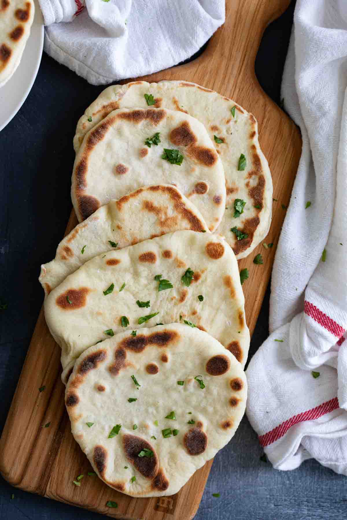 overhead view of naan bread on a cutting board with a white towel