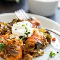 taco casserole on a plate topped with sour cream and cilantro
