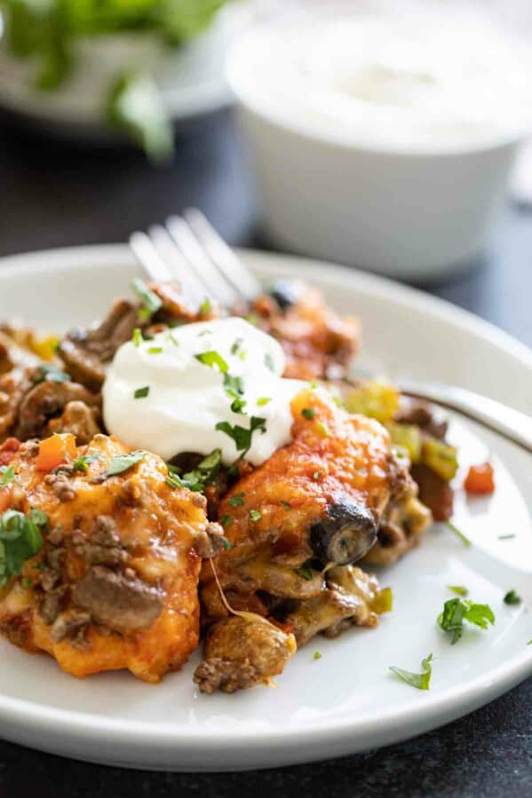 taco casserole on a plate topped with sour cream and cilantro
