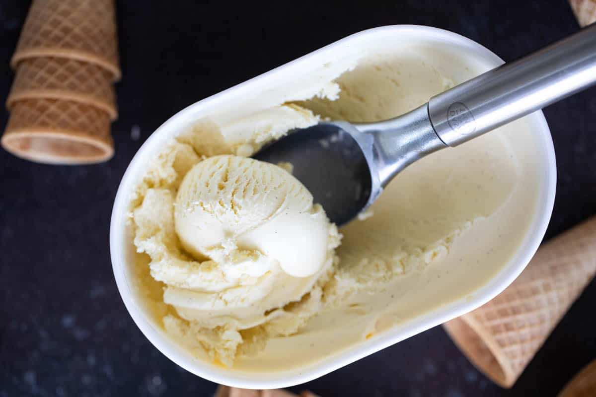 overhead view of carton of homemade vanilla ice cream with a scoop