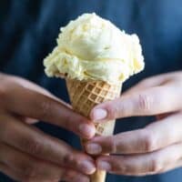 hands holding a scoop of ice cream in a sugar cone