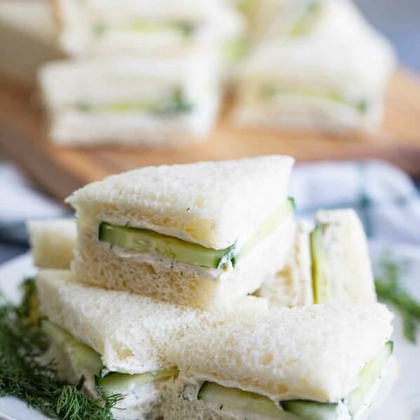 cucumber sandwiches stacked on a white plate