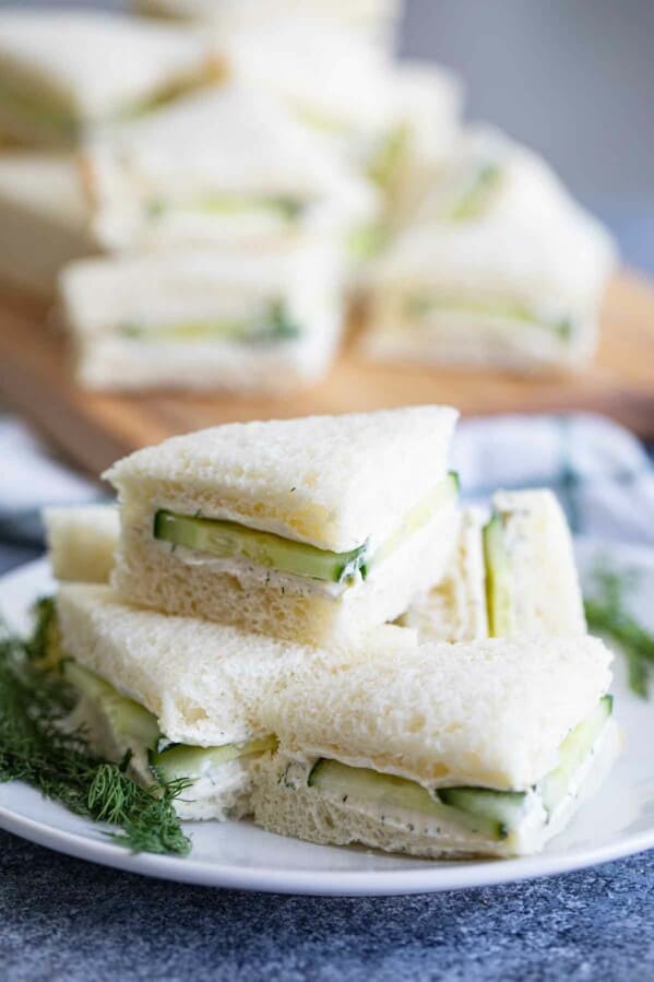 cucumber sandwiches stacked on a white plate