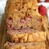 full loaf of strawberry bread cut on a cutting board.