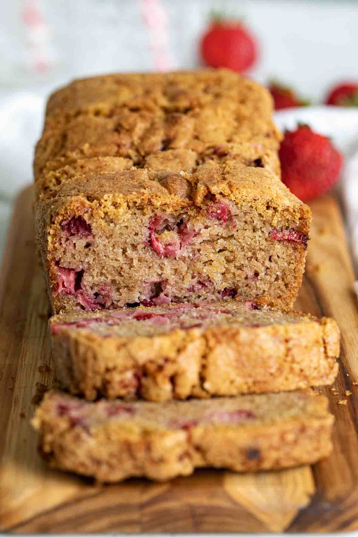 full loaf of strawberry bread cut on a cutting board.