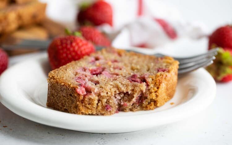 slice of strawberry bread on a plate with a bite taken from it.