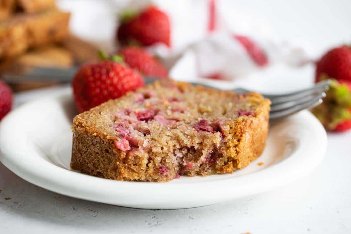 slice of strawberry bread on a plate with a bite taken from it.