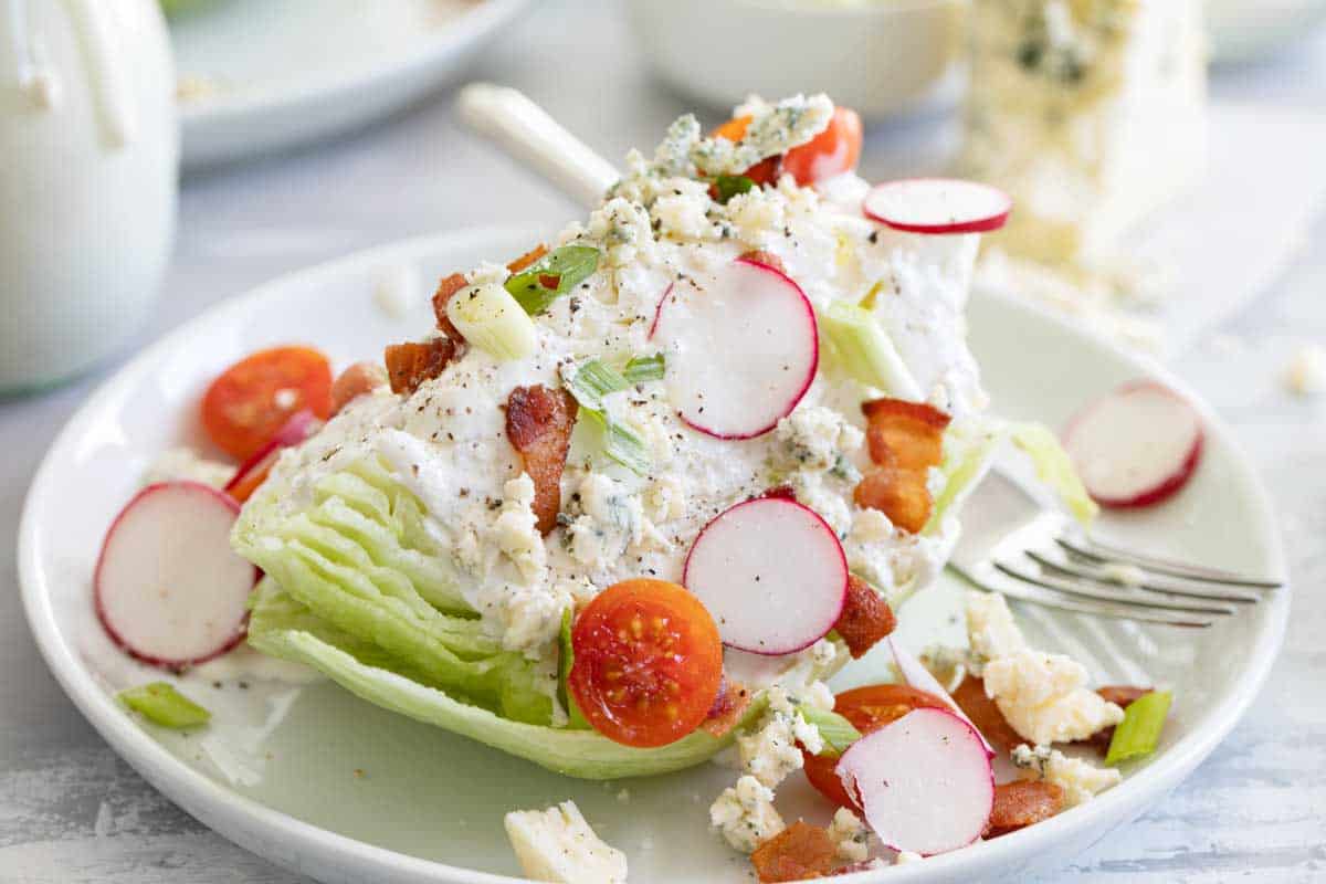 wedge salad on a plate topped with blue cheese dressing
