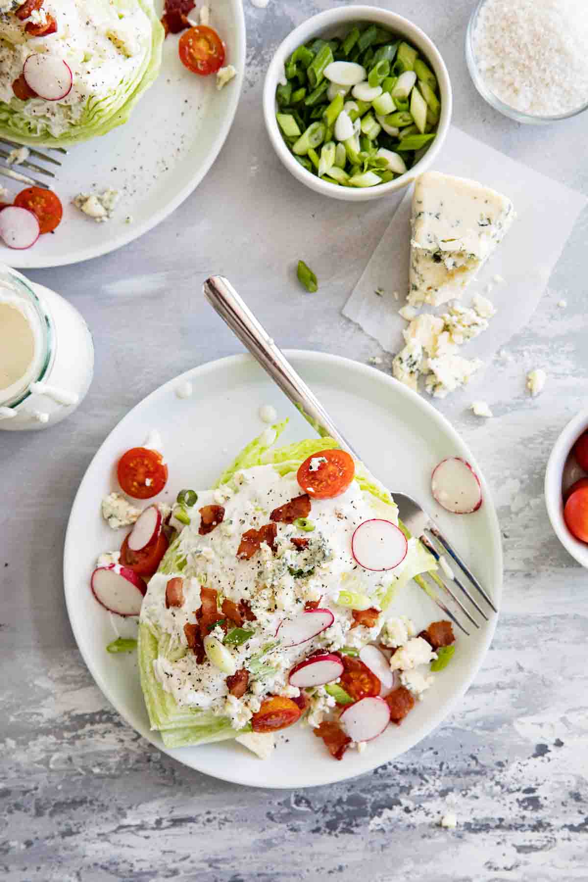 overhead view of wedge salad on plates with blue cheese and green onions