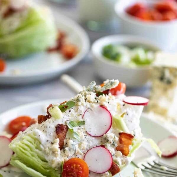 wedge salad on a plate with tomatoes, radishes and bacon
